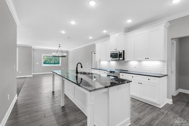 kitchen with appliances with stainless steel finishes, white cabinetry, a kitchen island with sink, and sink