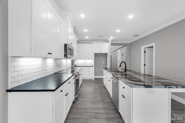 kitchen featuring white cabinets, appliances with stainless steel finishes, ornamental molding, and sink