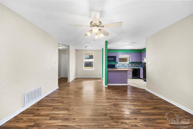 unfurnished living room featuring a textured ceiling, ceiling fan, and dark hardwood / wood-style floors