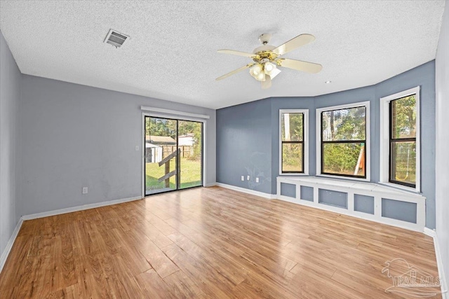 unfurnished room with a textured ceiling, ceiling fan, and light hardwood / wood-style flooring