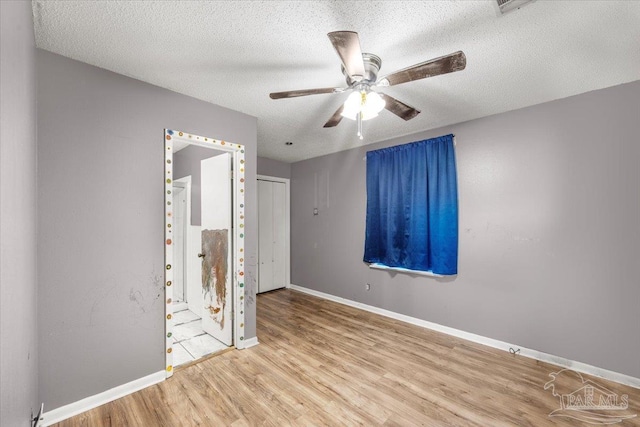 unfurnished bedroom with a textured ceiling, ceiling fan, and light hardwood / wood-style flooring