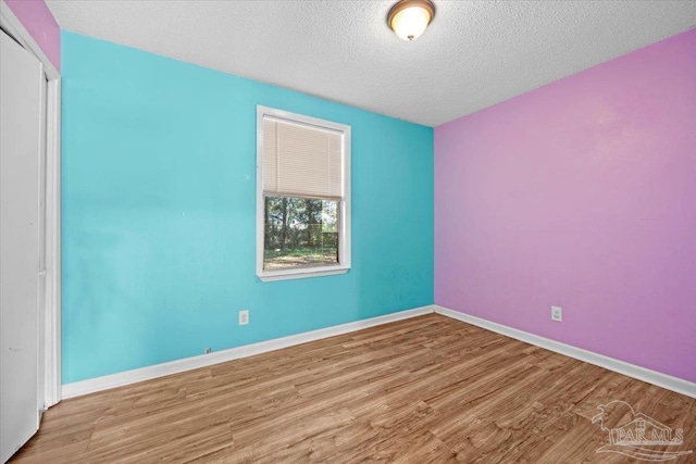 spare room featuring a textured ceiling and light hardwood / wood-style floors