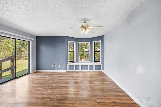 empty room with ceiling fan, hardwood / wood-style floors, and a textured ceiling