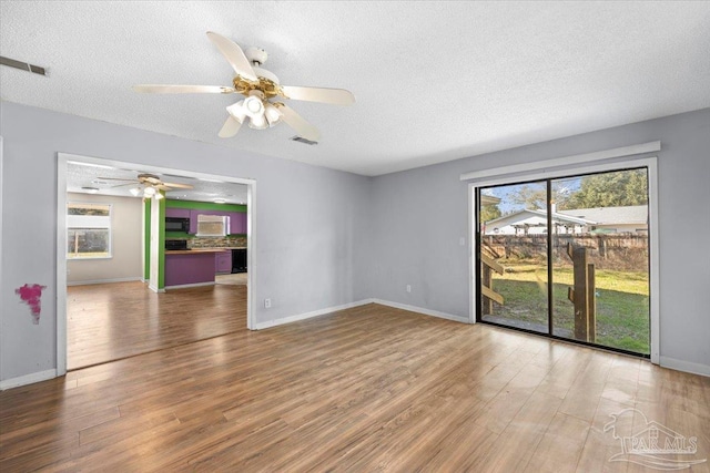 unfurnished room with a textured ceiling, hardwood / wood-style floors, and a wealth of natural light