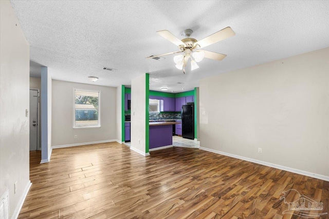 unfurnished living room featuring ceiling fan, a textured ceiling, and wood-type flooring