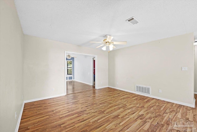 spare room with ceiling fan, a textured ceiling, and wood-type flooring