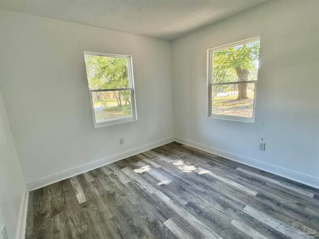 unfurnished room featuring dark wood-type flooring, a textured ceiling, and plenty of natural light