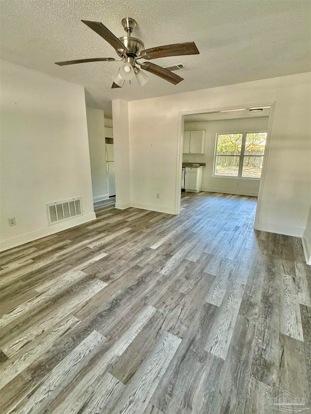 unfurnished living room featuring a textured ceiling, hardwood / wood-style floors, and ceiling fan