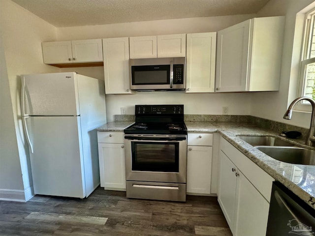 kitchen with light stone countertops, sink, white cabinets, and stainless steel appliances