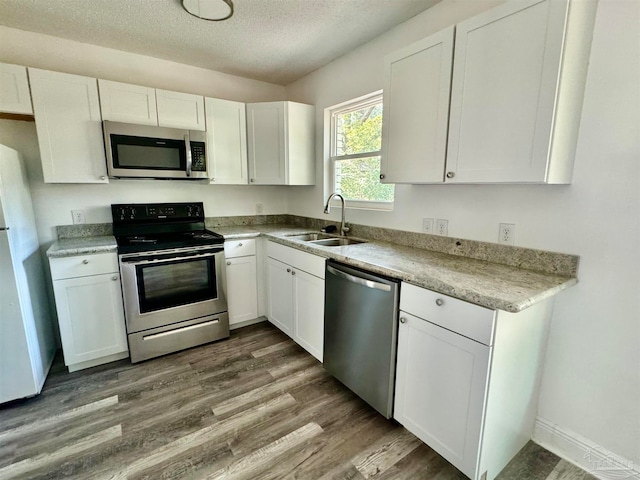 kitchen with appliances with stainless steel finishes, white cabinets, sink, and dark hardwood / wood-style floors