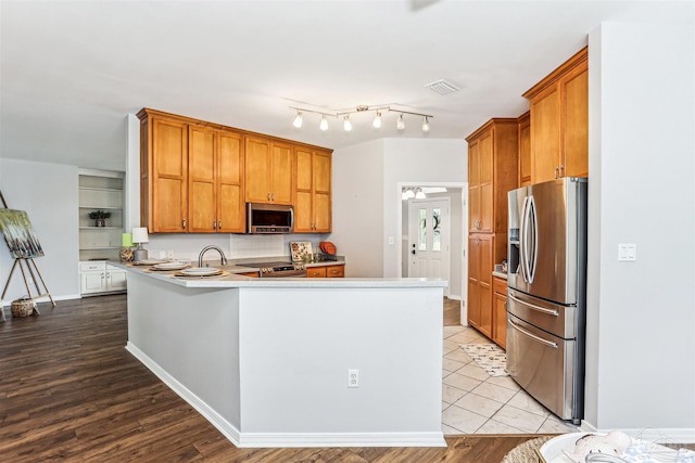 3640 Schifko Rd, Cantonment, FL 32533 - kitchen featuring stainless steel appliances, a peninsula, brown cabinets, and wood finished floors