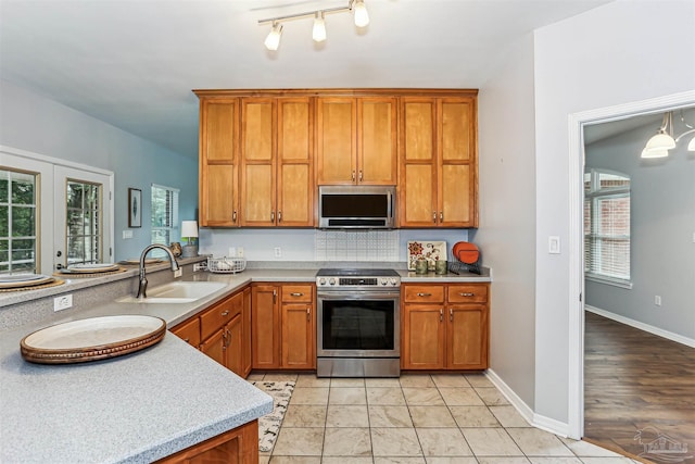 3640 Schifko Rd, Cantonment, FL 32533 - kitchen featuring stainless steel appliances, a sink, brown cabinetry, and plenty of natural light