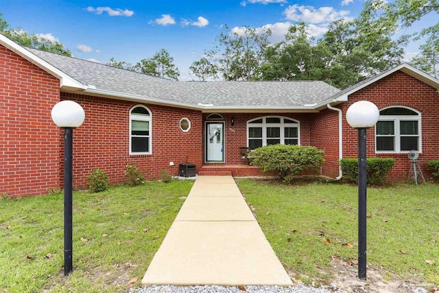 3640 Schifko Rd, Cantonment, FL 32533 - view of front facade featuring a front yard, roof with shingles, brick siding, and central AC unit