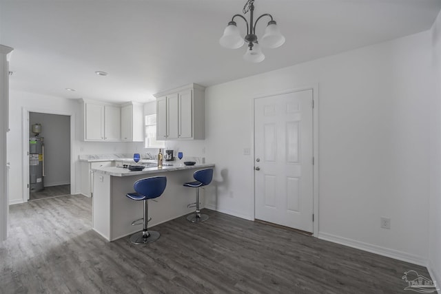 kitchen featuring a peninsula, white cabinets, light countertops, hanging light fixtures, and a kitchen bar