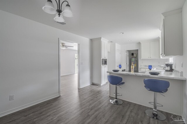 kitchen featuring light countertops, a breakfast bar, a peninsula, and white cabinetry