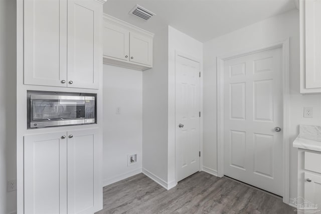 clothes washing area with light wood-style floors, visible vents, and baseboards