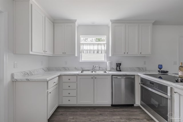 kitchen with dark wood finished floors, white cabinets, appliances with stainless steel finishes, light stone countertops, and a sink