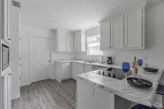 kitchen with light countertops, visible vents, white cabinetry, a sink, and built in microwave