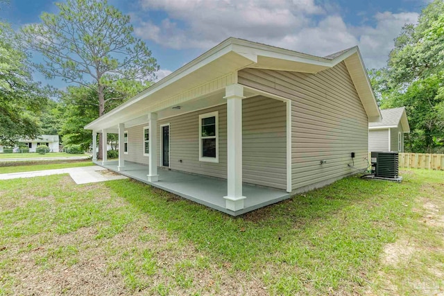 view of side of home with central air condition unit, fence, and a yard