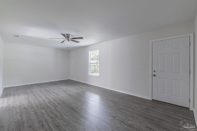 spare room featuring dark wood-style floors, visible vents, ceiling fan, and baseboards