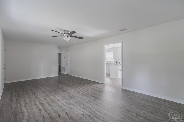 empty room featuring baseboards, visible vents, ceiling fan, and dark wood-type flooring