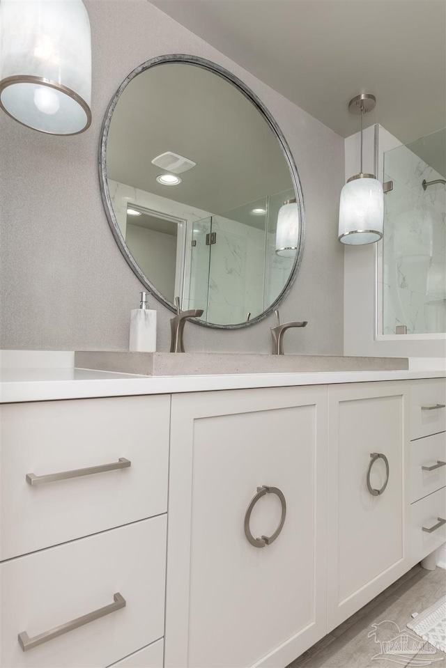 full bathroom featuring a marble finish shower, visible vents, vanity, and wood finished floors