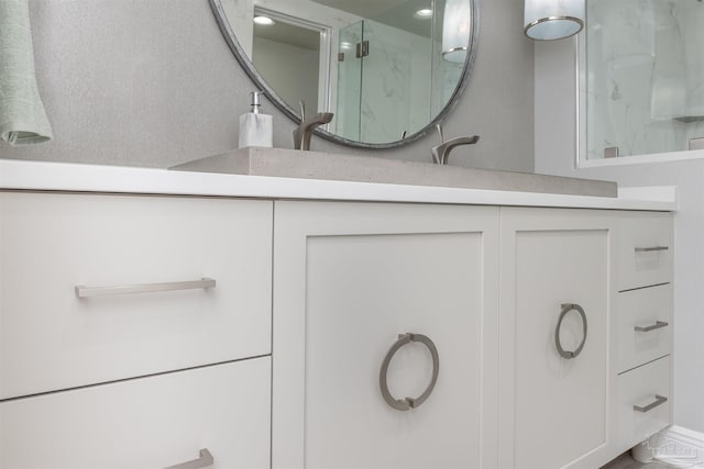 full bath featuring a marble finish shower and vanity