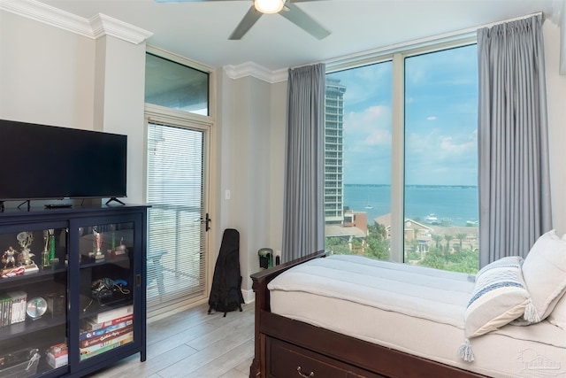 bedroom featuring ceiling fan, light wood-type flooring, crown molding, and a water view