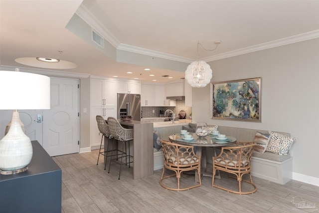 dining room featuring crown molding, light hardwood / wood-style flooring, and a notable chandelier