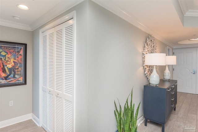 hallway featuring baseboards, crown molding, and light wood-style floors