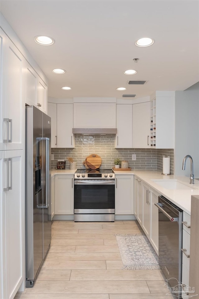 kitchen featuring premium range hood, sink, white cabinetry, appliances with stainless steel finishes, and light wood-type flooring