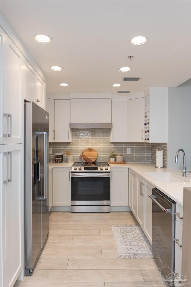 kitchen featuring light countertops, custom exhaust hood, appliances with stainless steel finishes, and a sink