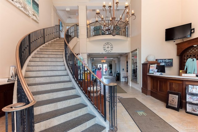 interior space featuring a towering ceiling, a chandelier, and decorative columns