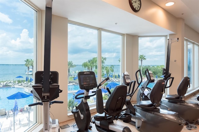 workout area with floor to ceiling windows and a water view