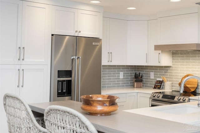 kitchen featuring custom exhaust hood, stainless steel appliances, tasteful backsplash, and white cabinetry