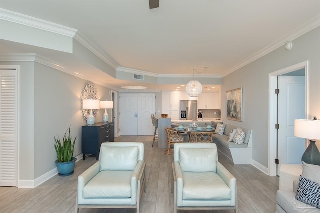 living room featuring baseboards, visible vents, light wood finished floors, and ornamental molding