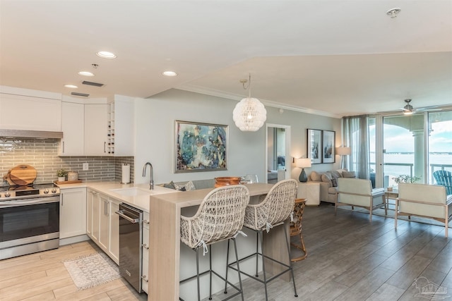 kitchen with appliances with stainless steel finishes, a breakfast bar, kitchen peninsula, and white cabinetry