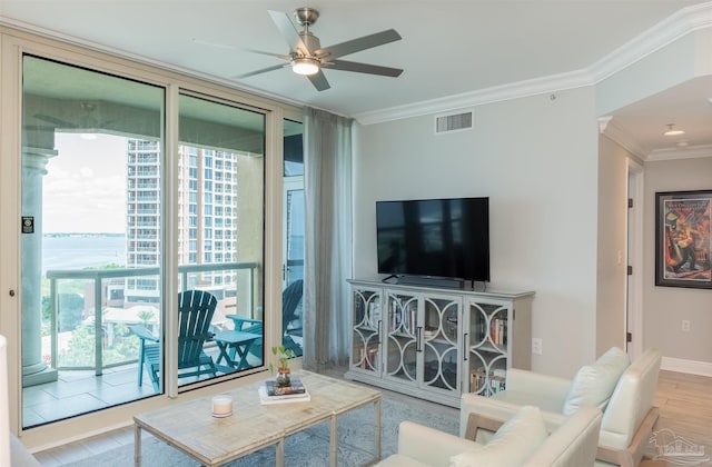 living area featuring visible vents, ornamental molding, a ceiling fan, wood finished floors, and a wall of windows
