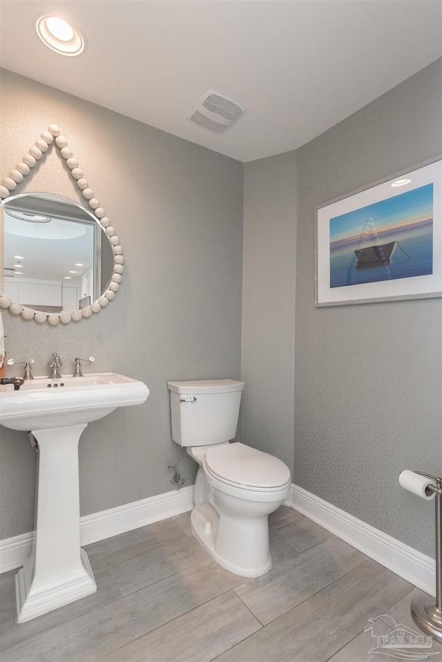 bathroom featuring visible vents, baseboards, toilet, and wood finished floors