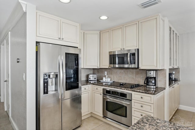 18 Via Deluna Dr Unit 603, Pensacola Beach, FL 32561 - kitchen with stainless steel appliances, dark stone countertops, cream cabinets, light tile patterned flooring, and recessed lighting
