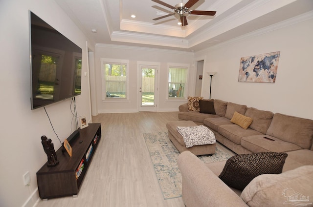 living room with light hardwood / wood-style floors, a tray ceiling, ornamental molding, and ceiling fan