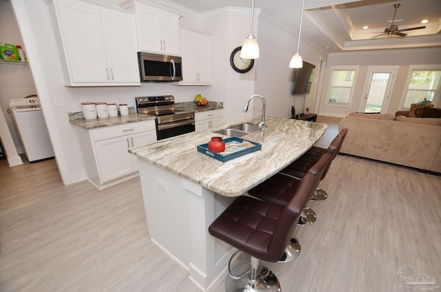 kitchen with washer / dryer, white cabinetry, appliances with stainless steel finishes, decorative light fixtures, and sink