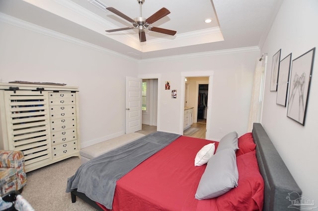 carpeted bedroom with ceiling fan, ornamental molding, connected bathroom, and a tray ceiling