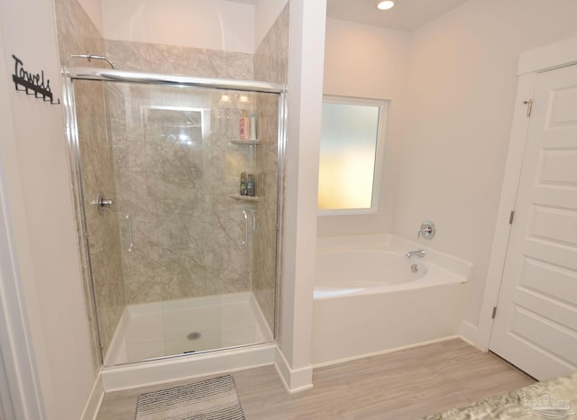 bathroom with shower with separate bathtub and hardwood / wood-style flooring