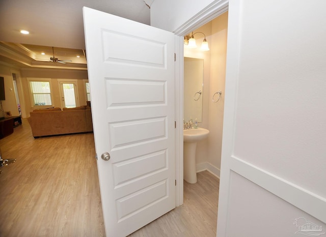 hallway with a raised ceiling and light wood-type flooring