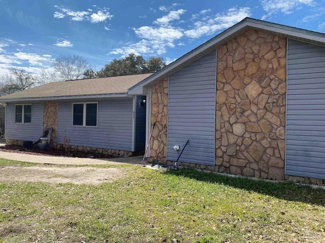 view of side of home with stone siding and a lawn