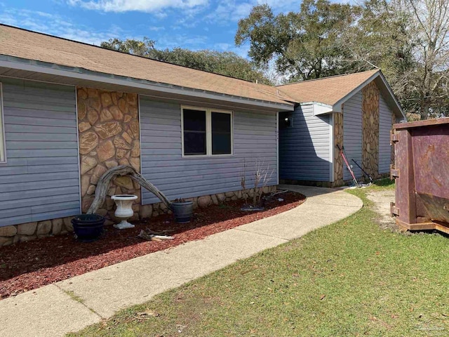 exterior space with stone siding and a yard