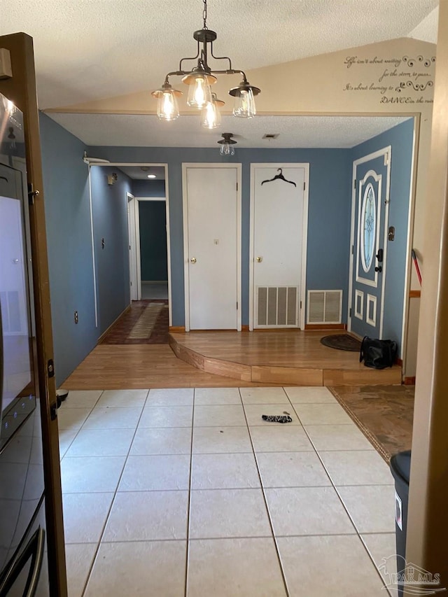 foyer with tile patterned flooring, visible vents, and a textured ceiling