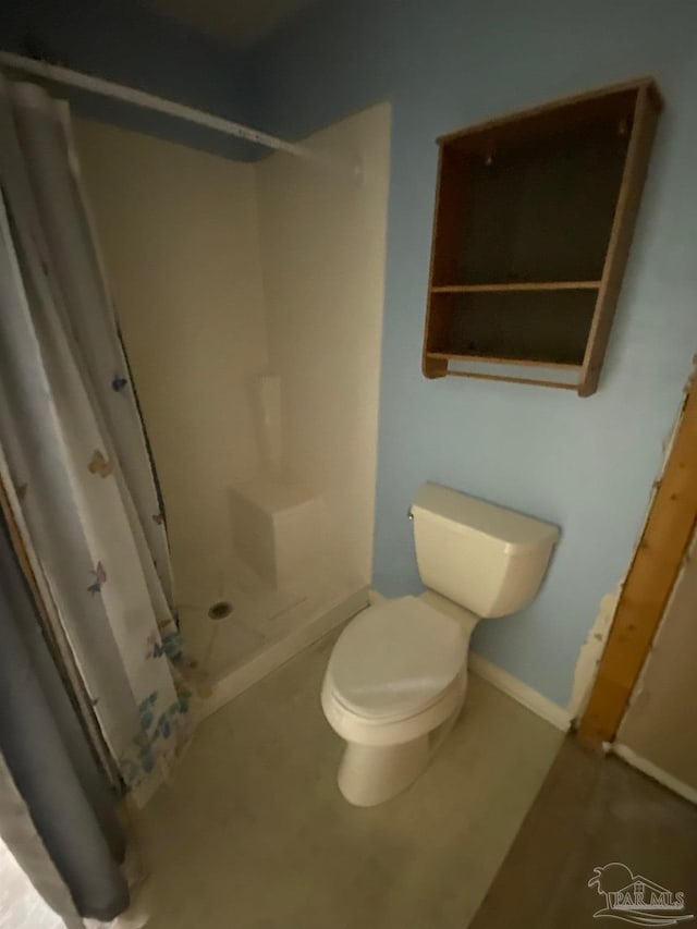 full bath featuring toilet, a stall shower, and baseboards