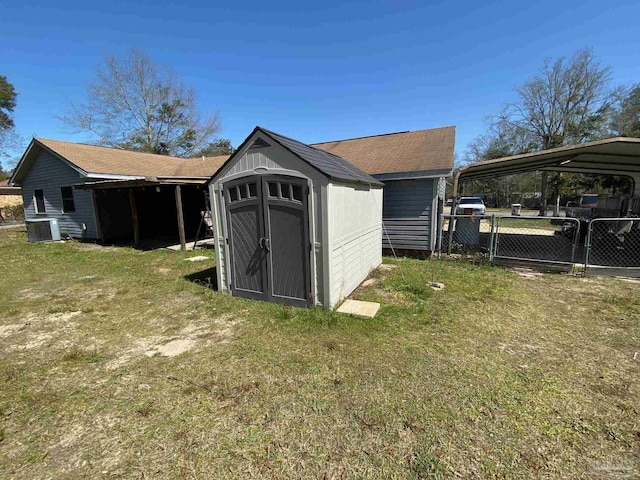 view of shed with a detached carport, central AC, fence, and a gate